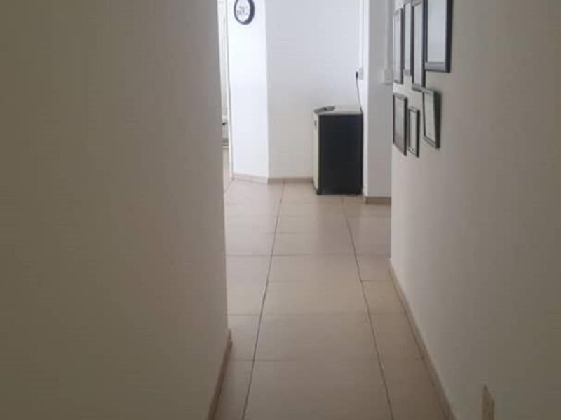A functional office hallway featuring neutral tiled flooring and clean white walls, providing access to adjacent workspaces.