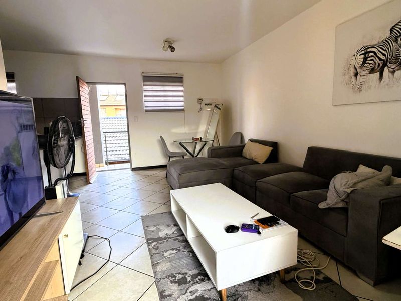 A functional living room featuring tiled flooring and direct access to an outdoor balcony area.
