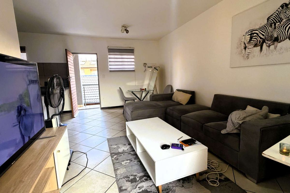 A functional living room featuring tiled flooring and direct access to an outdoor balcony area.
