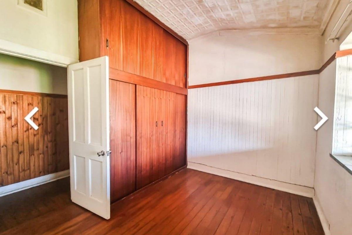 A bedroom featuring built-in timber wardrobes, original timber flooring, and decorative ceiling detailing.