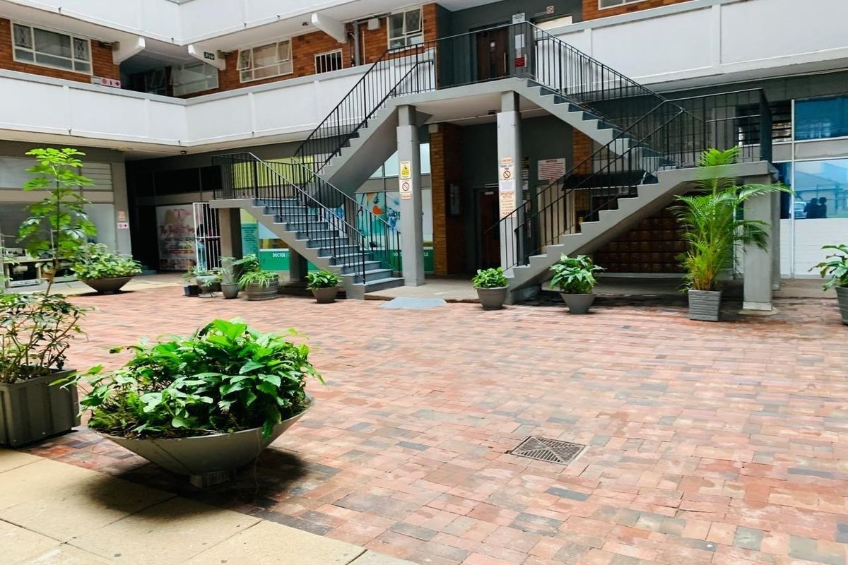 A communal courtyard area featuring brick paving, a central staircase with metal railings, and access to apartment building entrances.