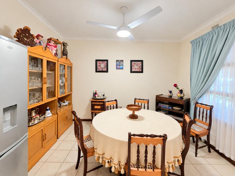 A functional dining room featuring tiled flooring, a central ceiling fan, and neutral wall finishes, providing a comfortable space for family meals.