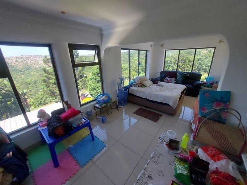 A bedroom featuring large windows with scenic views, tiled flooring, and recessed ceiling lighting.