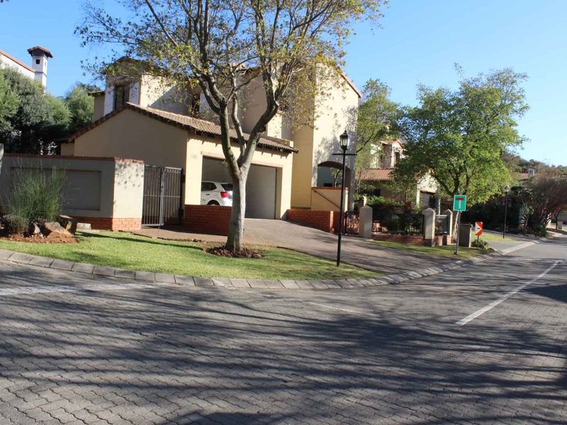 Front exterior view of the apartment complex featuring a paved driveway, garage access, and established garden landscaping.