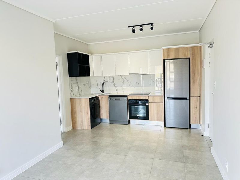 Modern kitchen featuring sleek two-tone cabinetry, marble-look splashback, integrated oven, electric hob, and tiled flooring in an open-plan layout.
