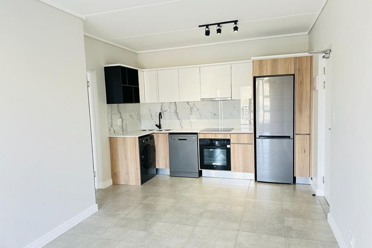 Modern kitchen featuring sleek two-tone cabinetry, marble-look splashback, integrated oven, electric hob, and tiled flooring in an open-plan layout.