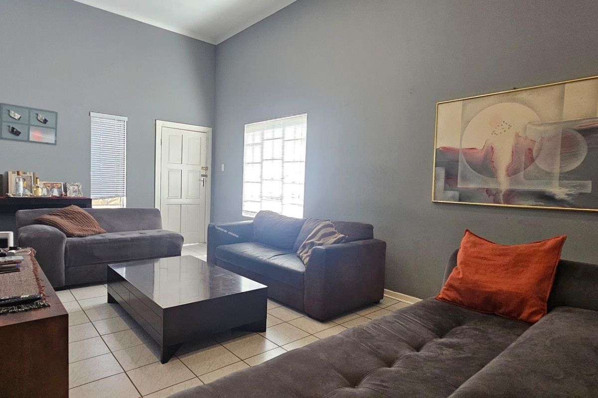 A spacious living room featuring high ceilings, tiled flooring, and natural light from multiple windows, providing a comfortable and functional living area.