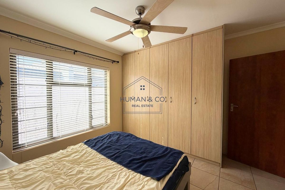 A well-maintained bedroom featuring built-in wooden cabinetry, tiled flooring, and a ceiling fan.