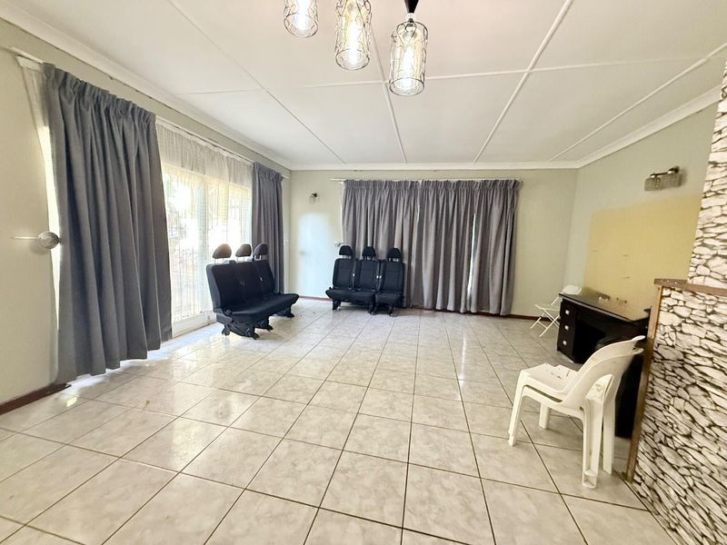 Spacious living room featuring tiled flooring, decorative ceiling panels, and a stone-clad feature wall, offering a versatile area for customization.
