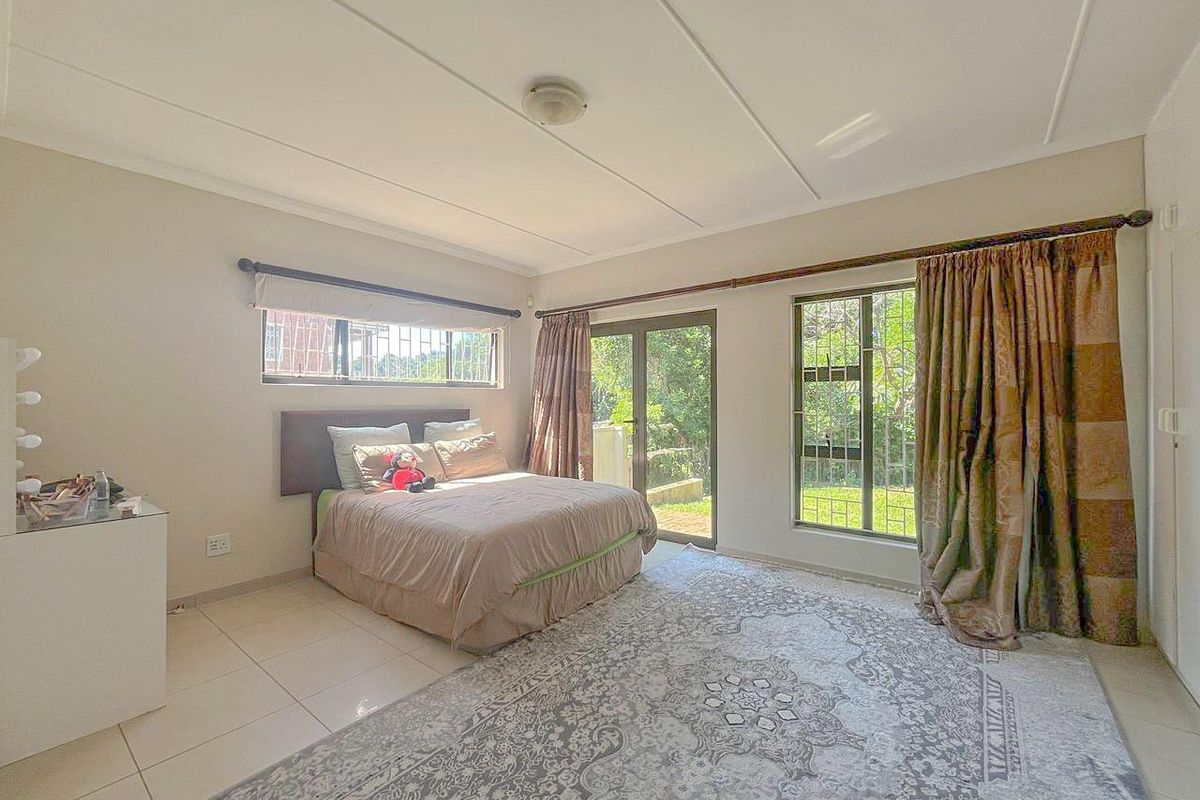 Spacious bedroom featuring tiled flooring, built-in cupboards, and large glass sliding doors providing direct access to the garden area.