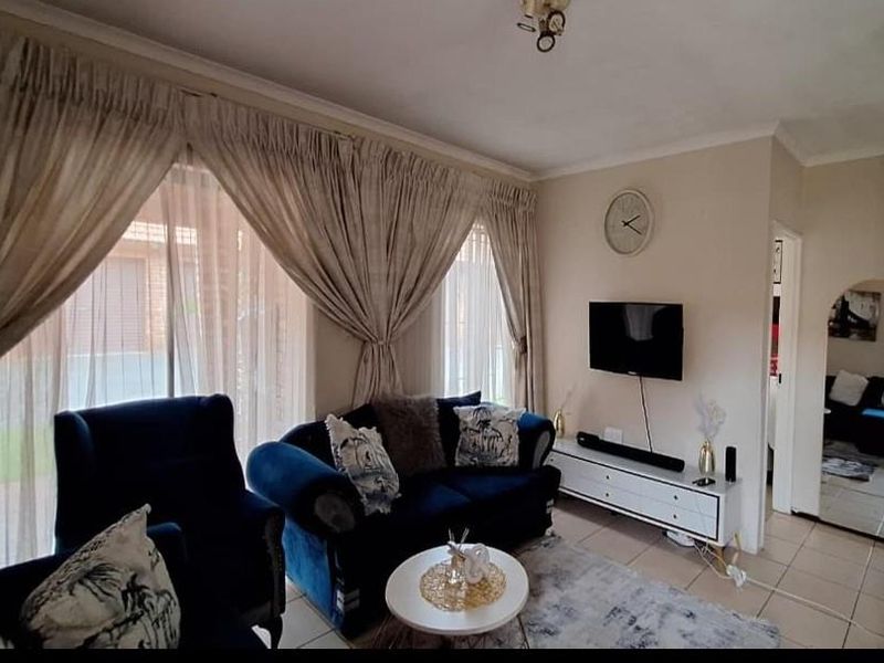 A comfortable living room featuring tiled flooring, coved ceilings, and large sliding glass doors that provide natural light and access to the exterior.