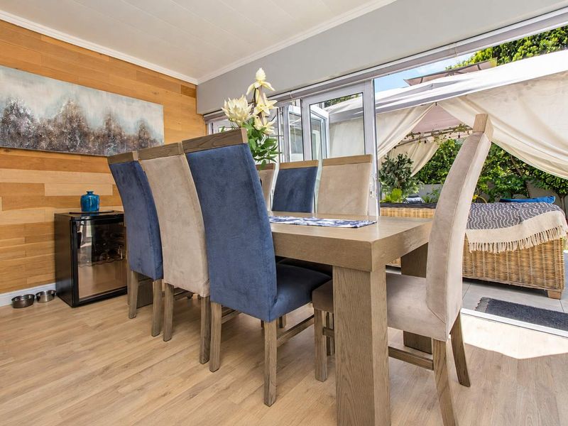 Dining area featuring timber wall cladding, light laminate flooring, and large sliding glass doors providing seamless access to the outdoor patio space.