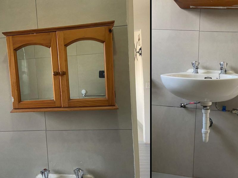 A bathroom featuring a wall-mounted basin and a wooden medicine cabinet against tiled walls.