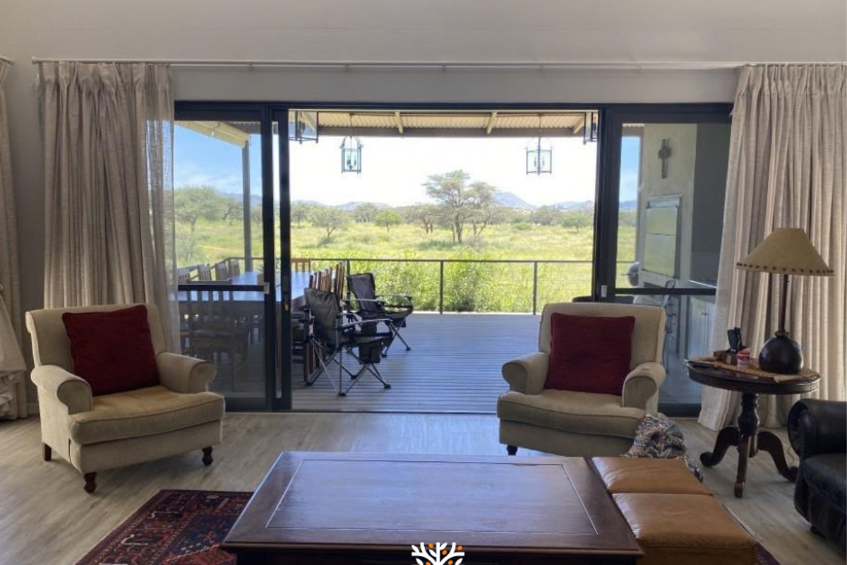 Spacious living room with vaulted ceilings and large sliding glass doors opening onto a covered patio with scenic bushveld views.