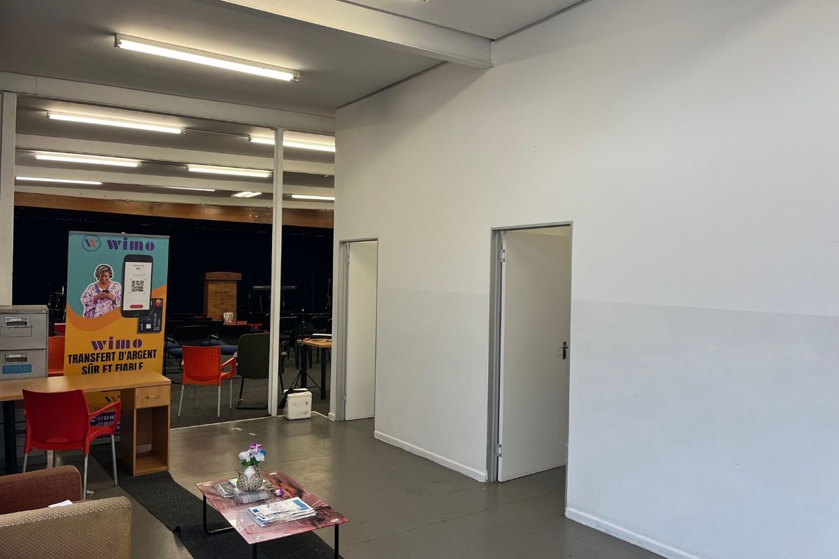 Open plan commercial or multi-purpose space featuring painted concrete floors and fluorescent lighting, with access to adjacent rooms via internal doorways.