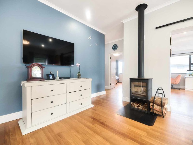 A bright living room featuring polished hardwood flooring and a prominent black wood-burning fireplace, creating a warm and inviting atmosphere.