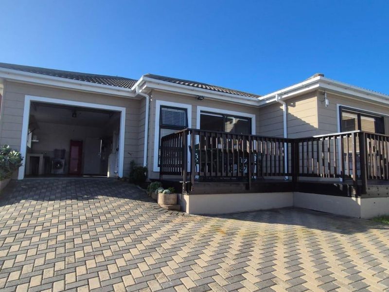 Front exterior view of the townhouse featuring a paved driveway, integrated garage, and a raised timber deck with balustrade.