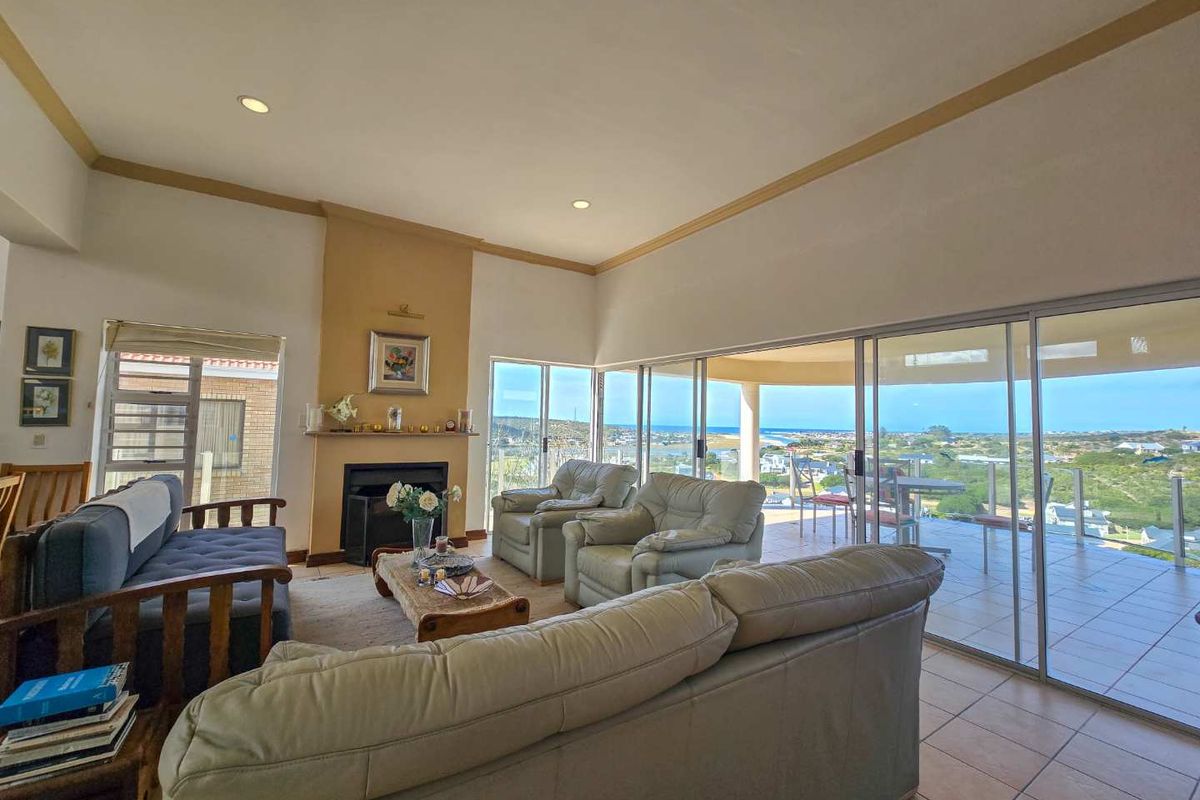 Spacious living room featuring a built-in fireplace, tiled flooring, and large sliding glass doors opening onto a balcony with expansive coastal views.
