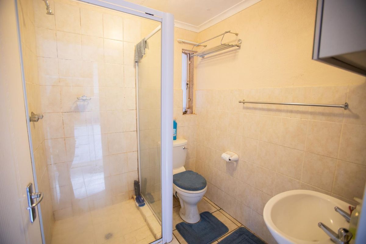 A compact bathroom featuring a glass-enclosed shower, a standard toilet, and a wall-mounted basin with tiled walls.