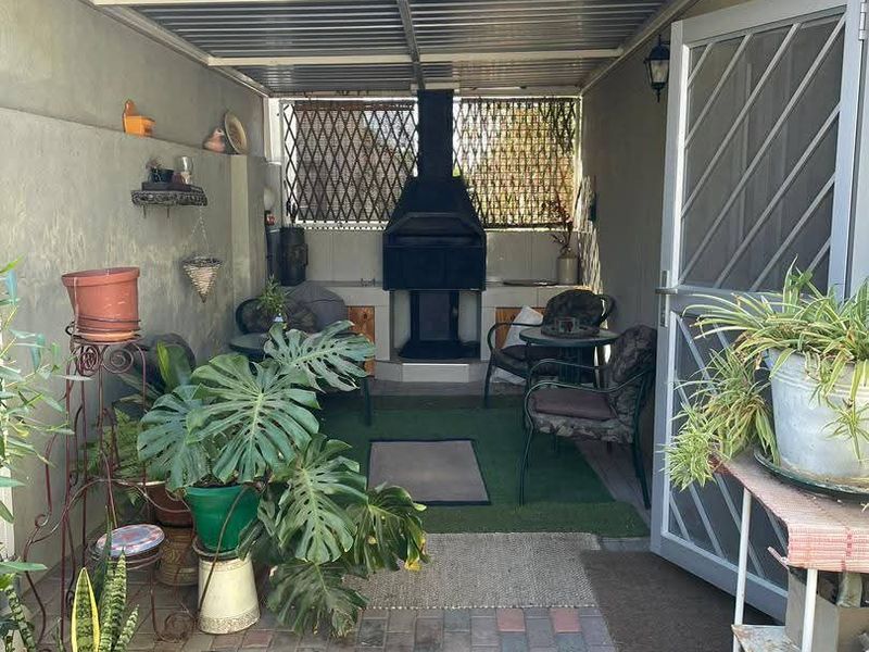 Covered patio area featuring a built-in braai, paved flooring, and a secure entrance gate, providing a functional outdoor entertainment space.
