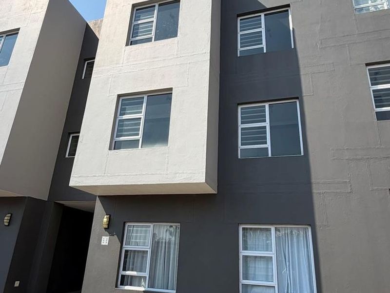 Modern multi-story apartment building facade featuring a contemporary grey and white color scheme with aluminium window frames and exterior lighting.