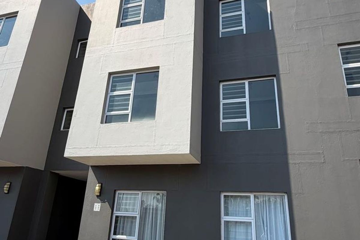 Modern multi-story apartment building facade featuring a contemporary grey and white color scheme with aluminium window frames and exterior lighting.