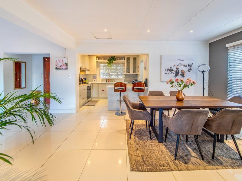 Spacious open-plan living and dining area featuring polished tiled floors, recessed lighting, and a modern kitchen with built-in appliances and a central island.