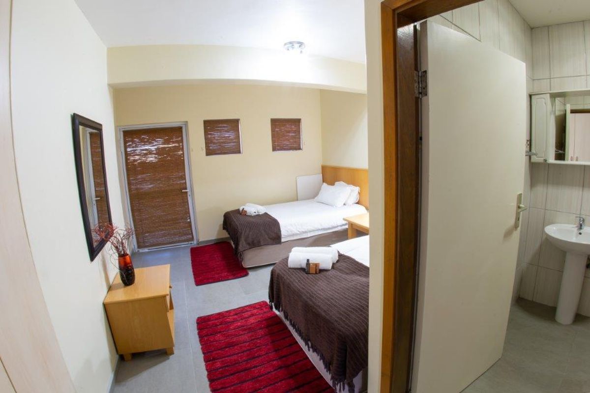 A bedroom featuring tiled flooring and an en-suite bathroom with a pedestal sink, providing functional living space.