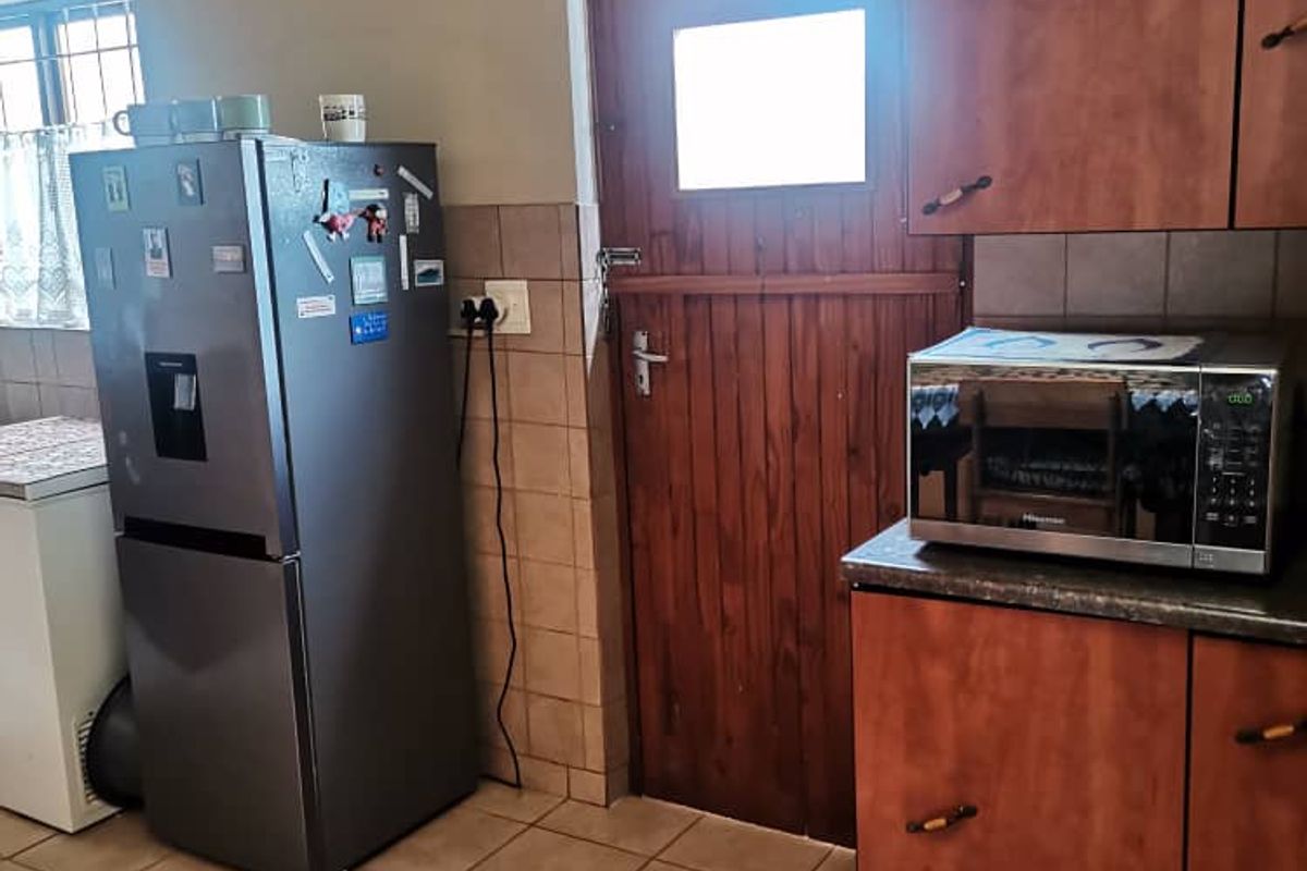 A functional kitchen area featuring wooden cabinetry, tiled flooring, and a stable-style wooden door leading to the exterior.
