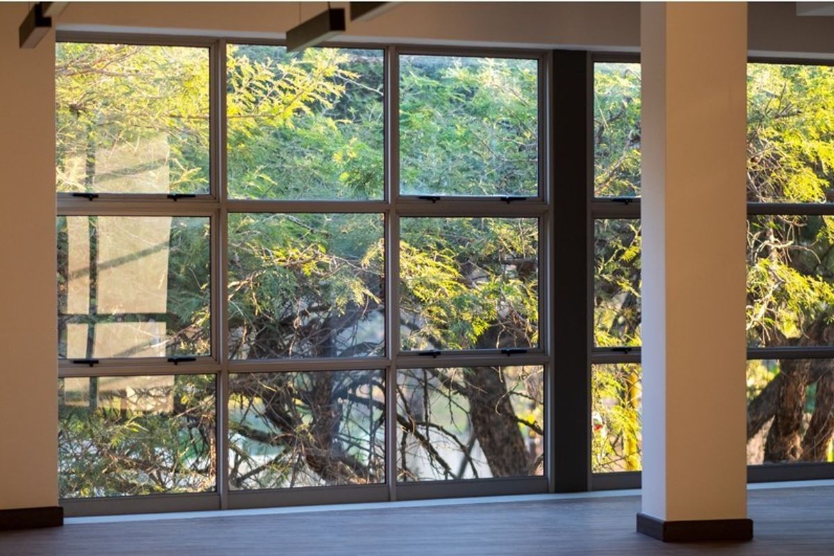 A bright, open-plan office space featuring large windows with natural views and a clean, modern structural column.