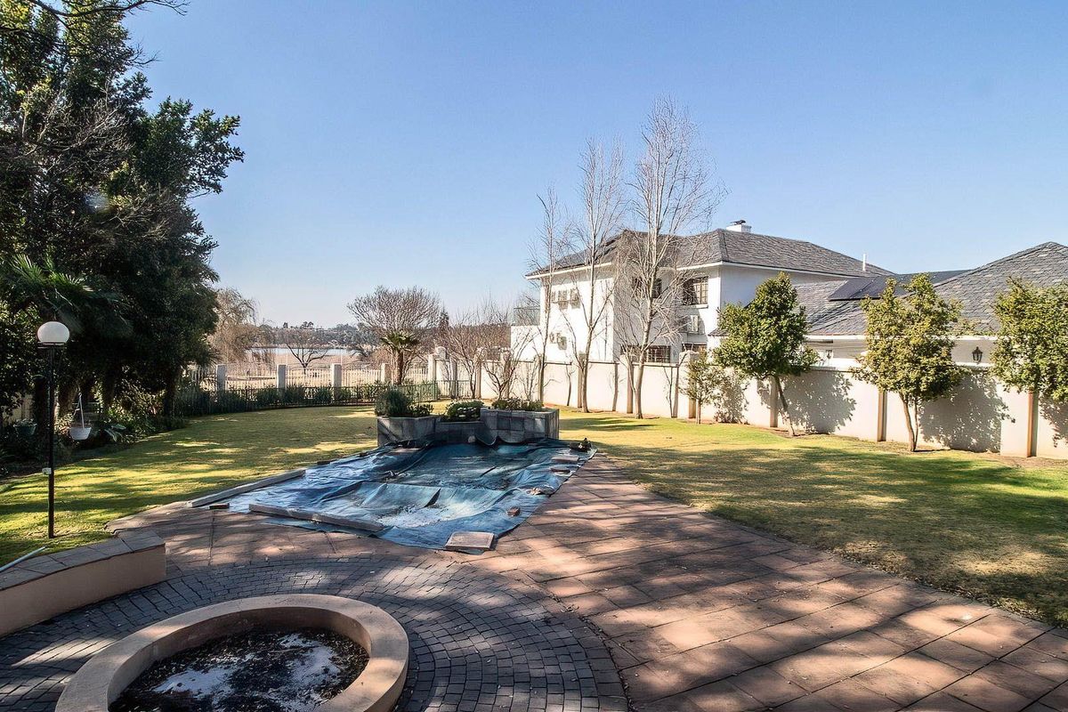 Spacious rear garden featuring a paved patio area, a swimming pool with a cover, and established lawn space.