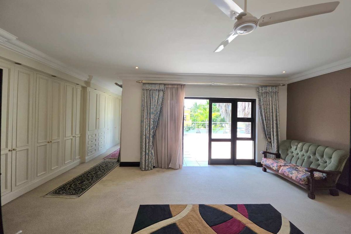 Spacious bedroom featuring extensive built-in cabinetry, a ceiling fan, and direct access to an outdoor patio area through sliding glass doors.