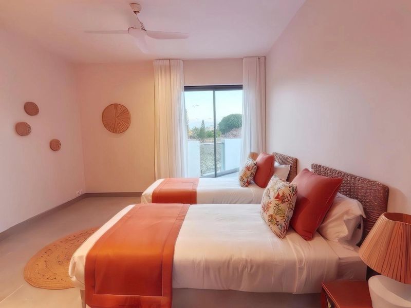 A well-maintained bedroom featuring tiled flooring, a ceiling fan, and a sliding glass door providing direct access to a private balcony.