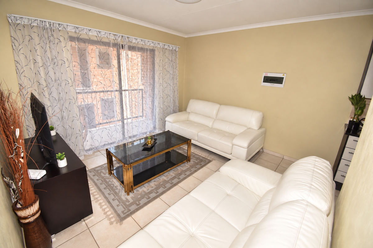 A living room featuring tiled flooring and a sliding glass door providing access to the exterior.