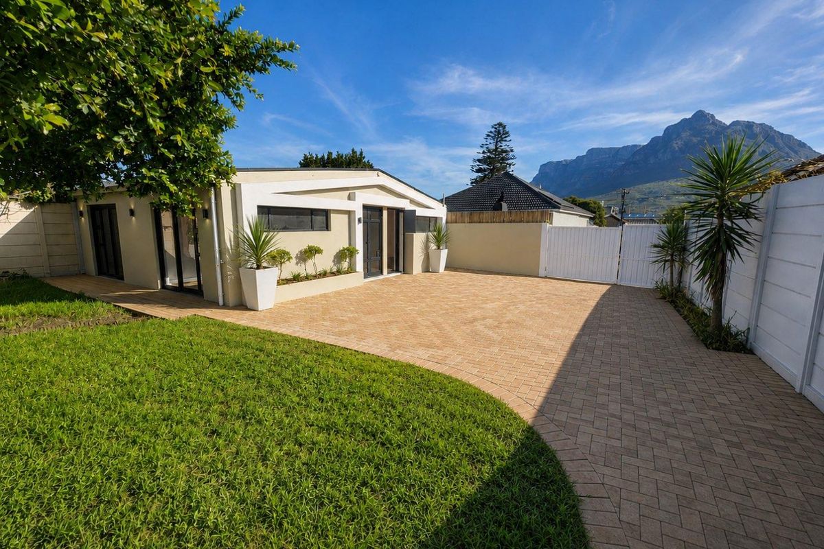 A well-maintained rear exterior featuring a paved courtyard, manicured lawn, and mountain views, providing a clean and inviting outdoor space.