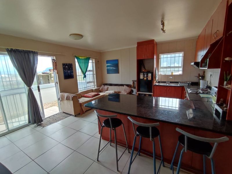 Open-plan living and kitchen area featuring granite countertops, built-in cabinetry, tiled flooring, and direct access to an outdoor balcony through a sliding glass door.
