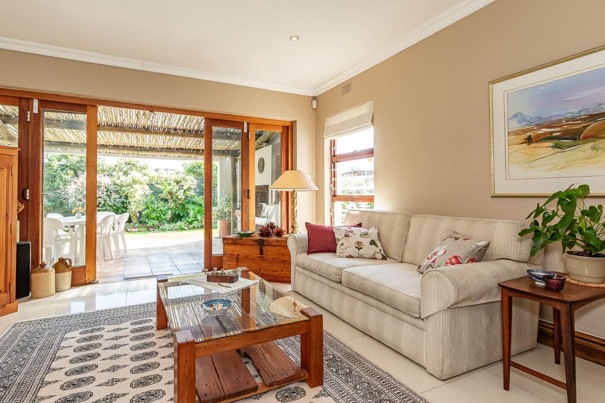 A bright living room featuring large wooden sliding doors that open onto a covered patio and garden area, creating a seamless indoor-outdoor flow.