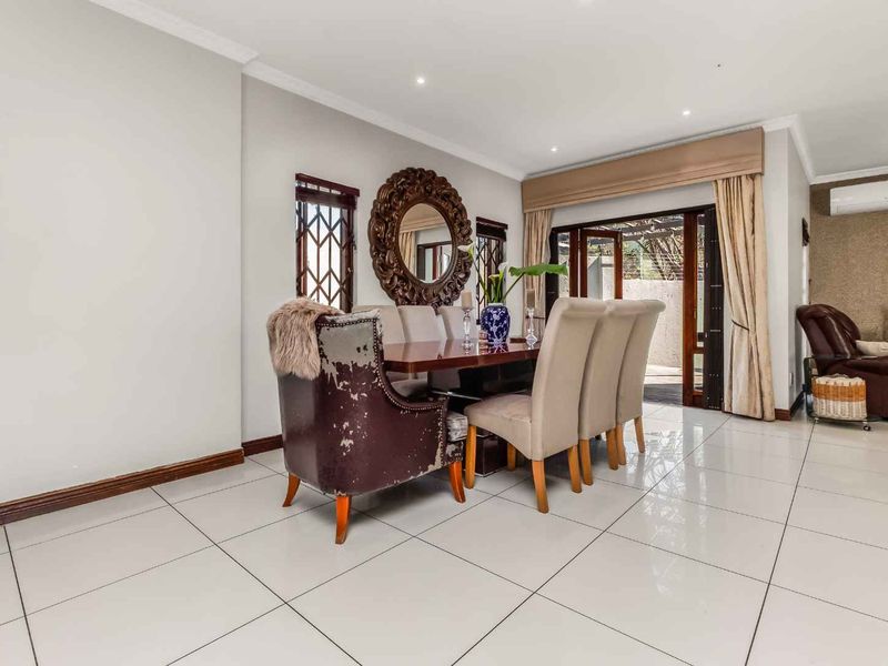A bright dining room featuring large format floor tiles, recessed lighting, and sliding glass doors providing access to the outdoor area.