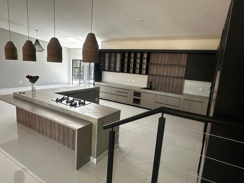 Modern open-plan kitchen featuring a large island with a built-in gas hob, sleek cabinetry, and contemporary slatted wood detailing.