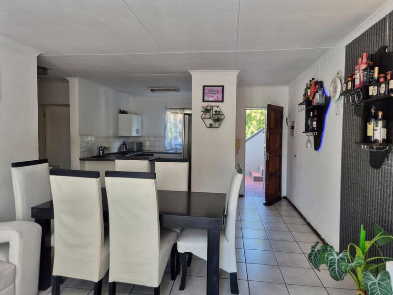 Open plan living and dining area featuring tiled flooring and a functional kitchen space with direct access to the exterior.