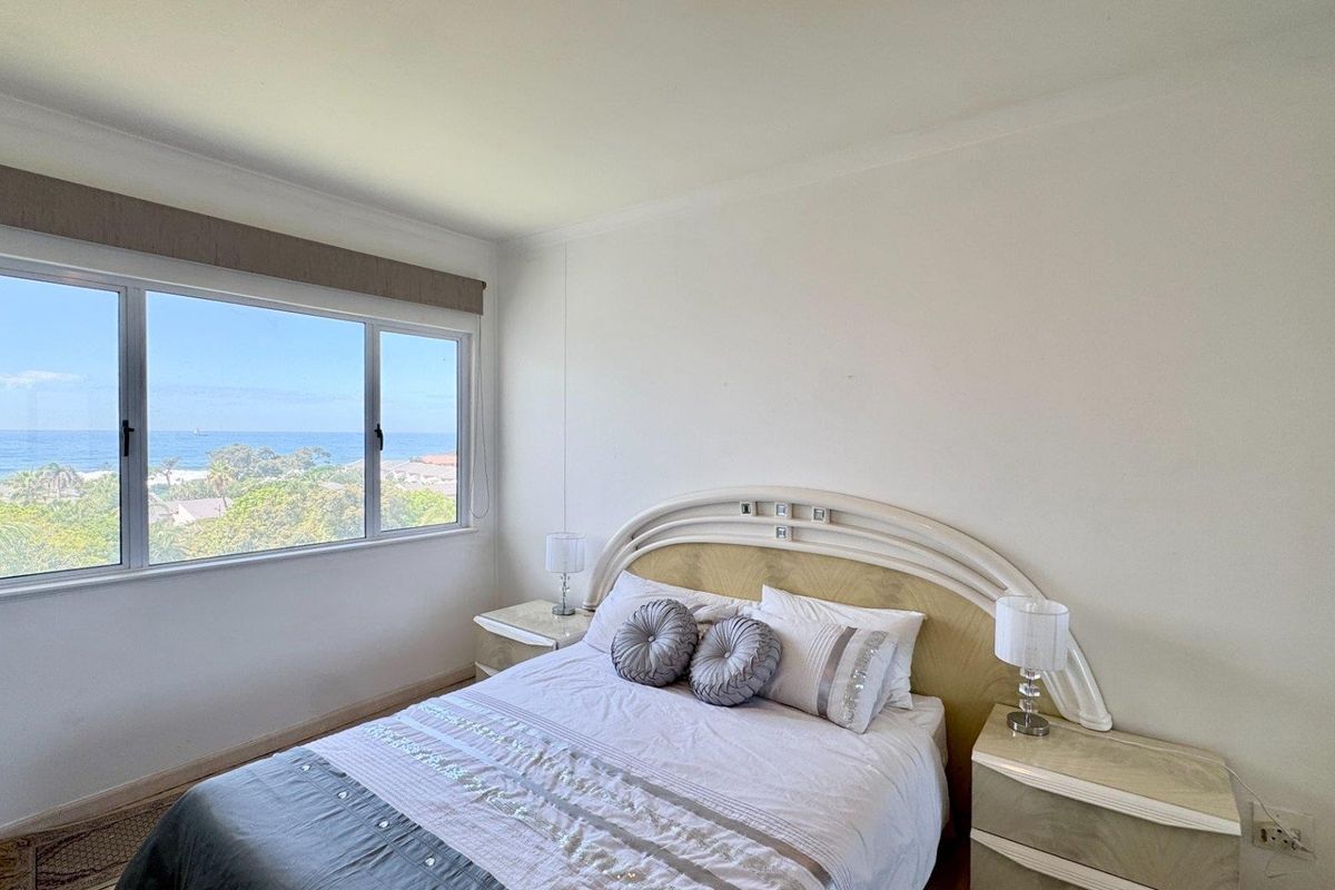 A bright bedroom featuring a large window with scenic ocean views and neutral wall finishes.