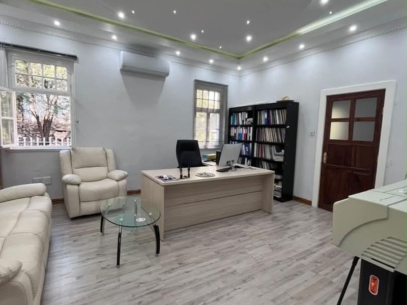 A well-maintained office space featuring modern laminate flooring, recessed ceiling lighting with cove accents, and a split-system air conditioner.