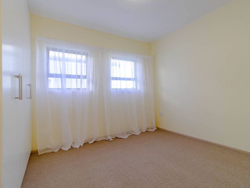 A clean, empty bedroom featuring neutral walls, carpeted flooring, and a built-in wardrobe, offering a blank canvas for personalization.