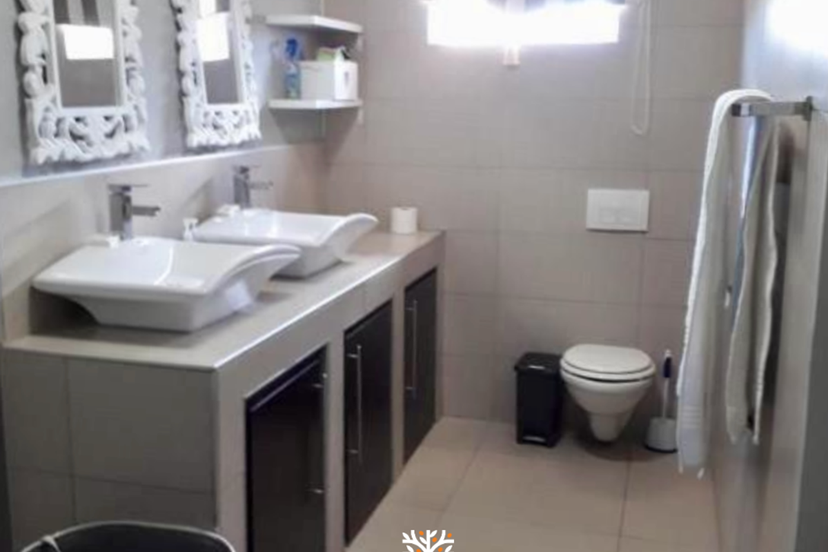 Modern bathroom featuring a double vanity with vessel sinks, wall-mounted toilet, and neutral floor-to-ceiling tiling.