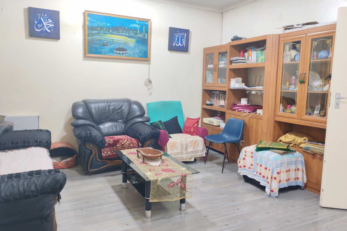 A living room featuring light-toned laminate flooring and a large built-in wooden shelving unit providing ample storage space.