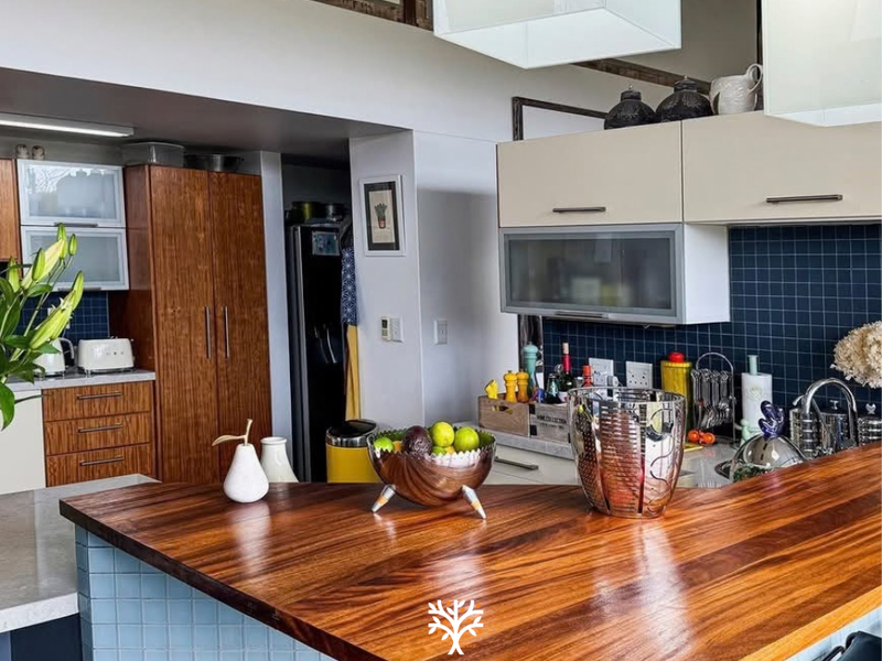 A functional kitchen featuring a prominent wooden breakfast bar, dark tiled backsplash, and ample built-in cabinetry for storage.