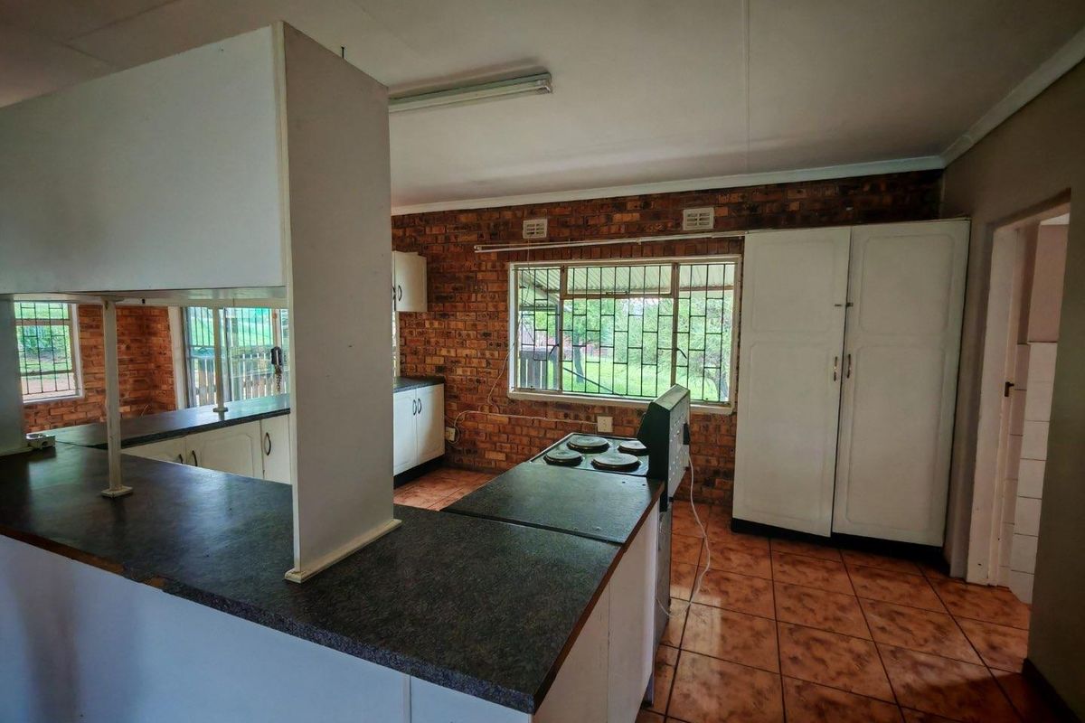 A functional kitchen featuring exposed brick walls, tiled flooring, built-in cabinetry, and a stove, offering a rustic aesthetic with potential for modernization.