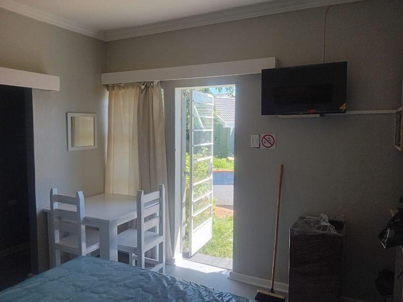 A bedroom featuring a security gate leading to an outdoor area, neutral wall finishes, and coving detail.
