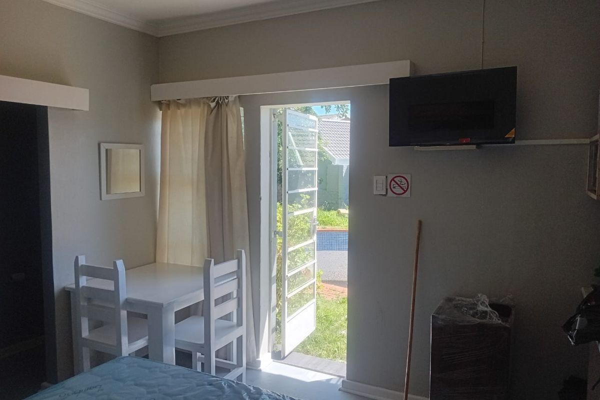 A bedroom featuring a security gate leading to an outdoor area, neutral wall finishes, and coving detail.