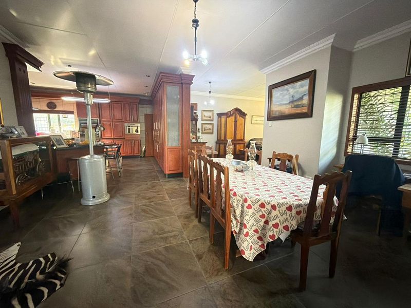 Spacious open-plan living and dining area featuring tiled flooring, built-in kitchen cabinetry, and classic cornicing, offering a functional layout for family living.